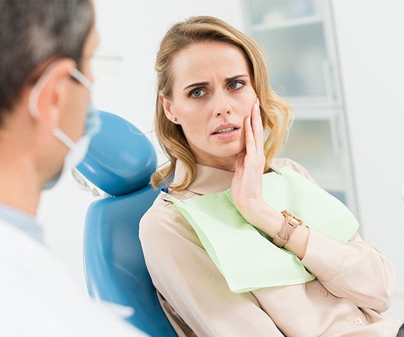 Woman at emergency dentistry visit holding cheek